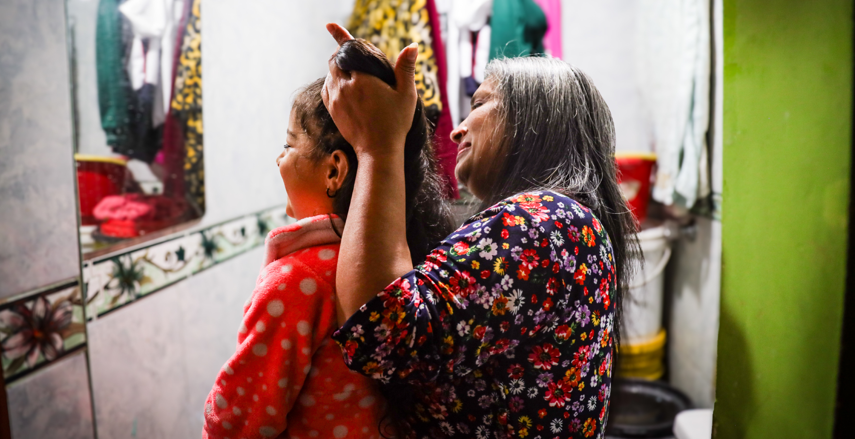 Mujer cuidadora peinando cabello a su nieta