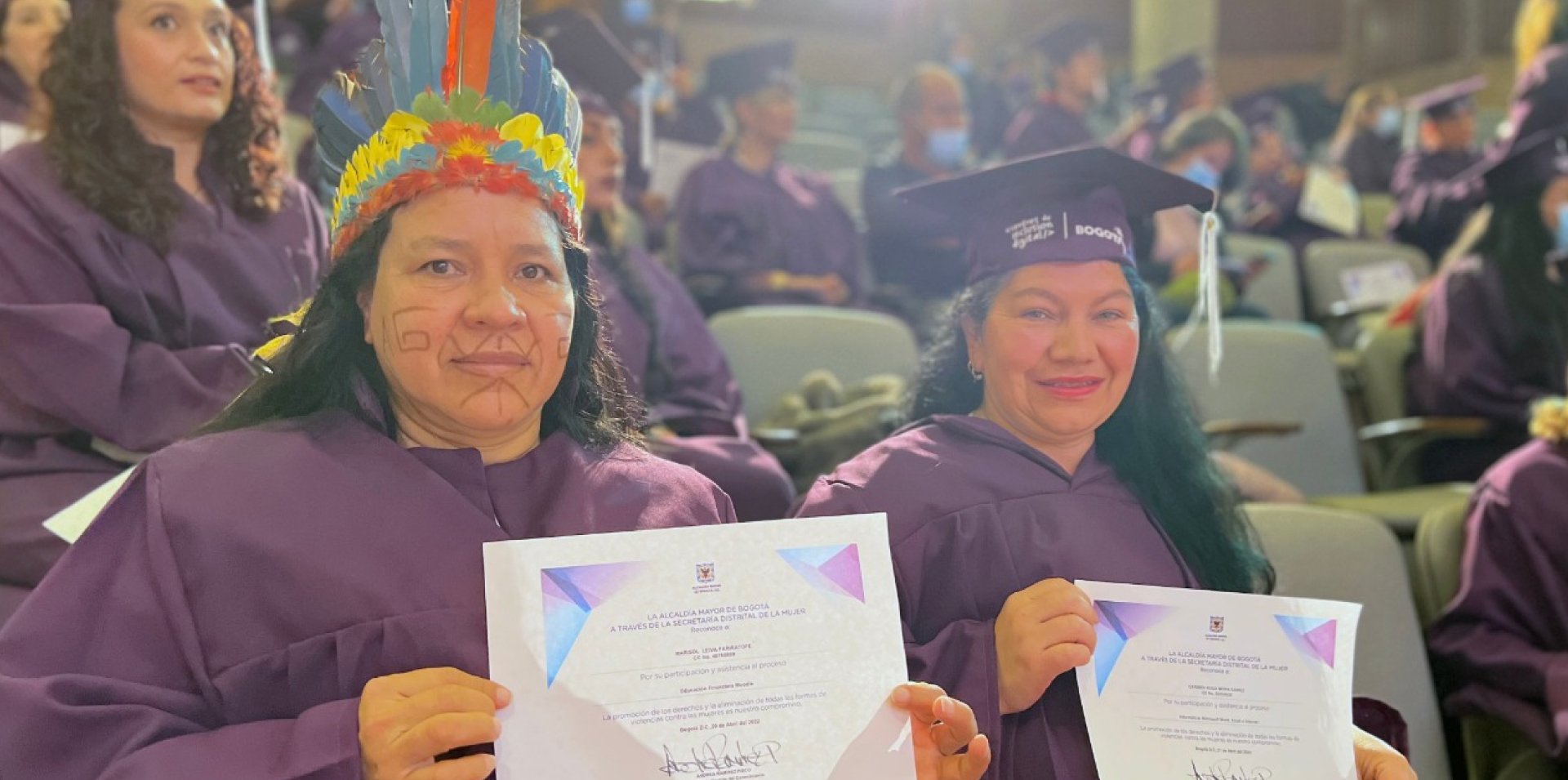 Mujer indígena y mujer de localidad con su diploma de graduación