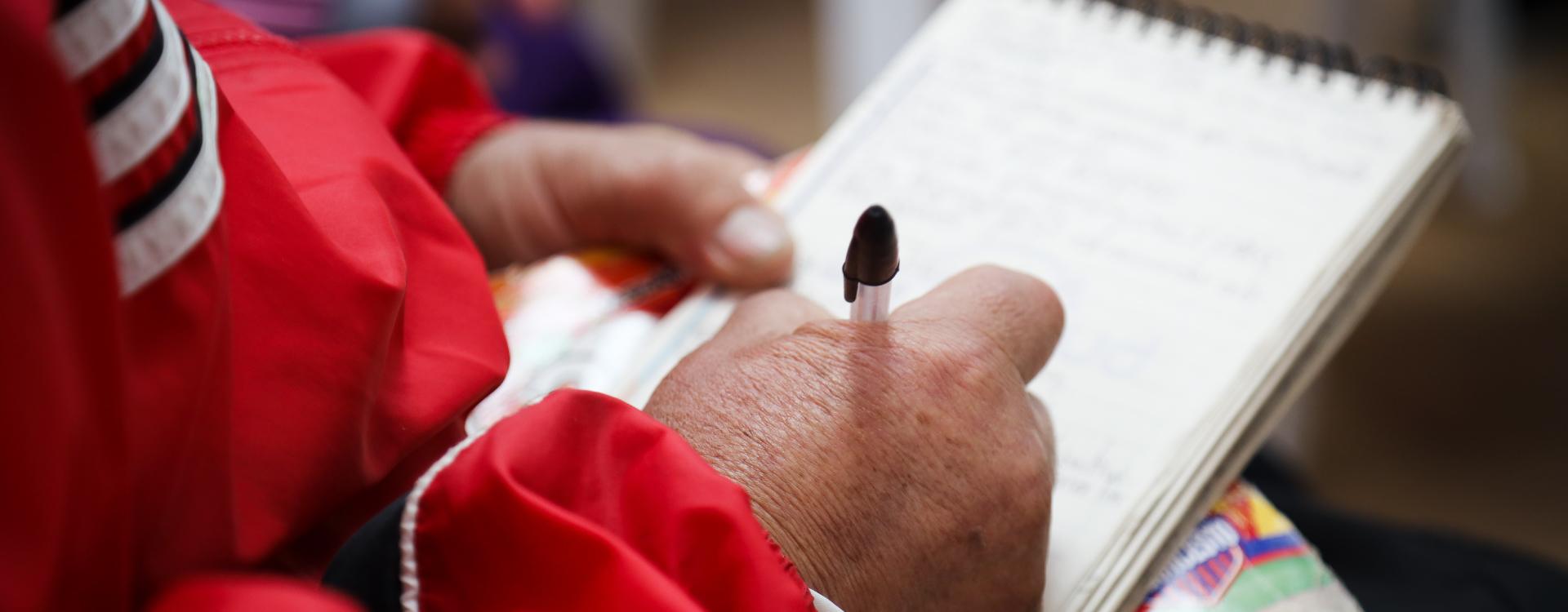 Manos de mujer mayor escribiendo en libreta