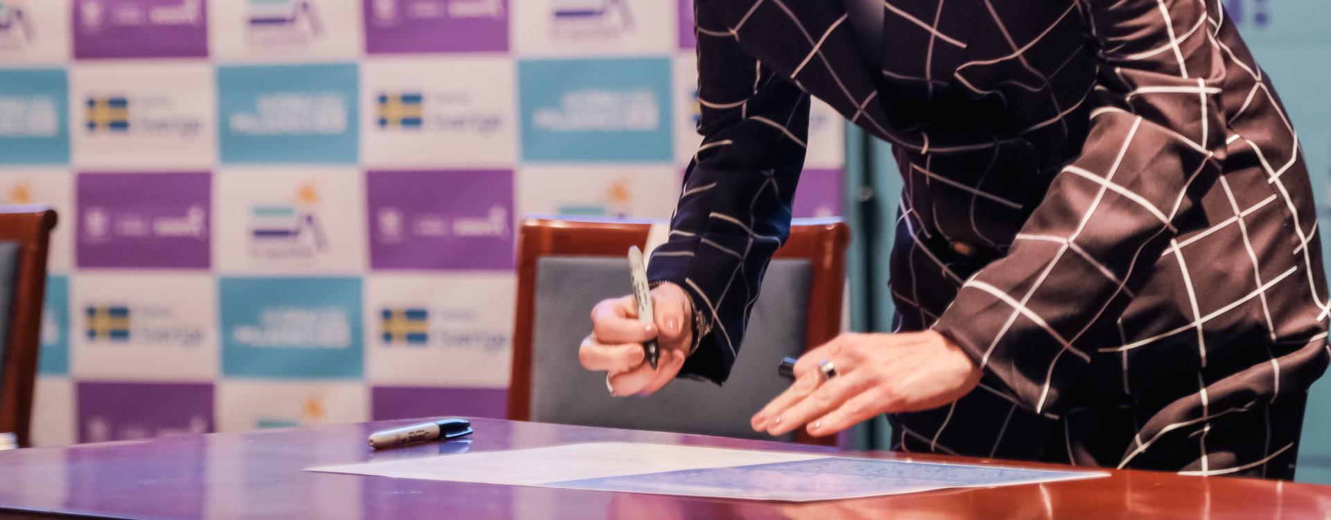 Mujer firmando pacto por la igualdad en evento