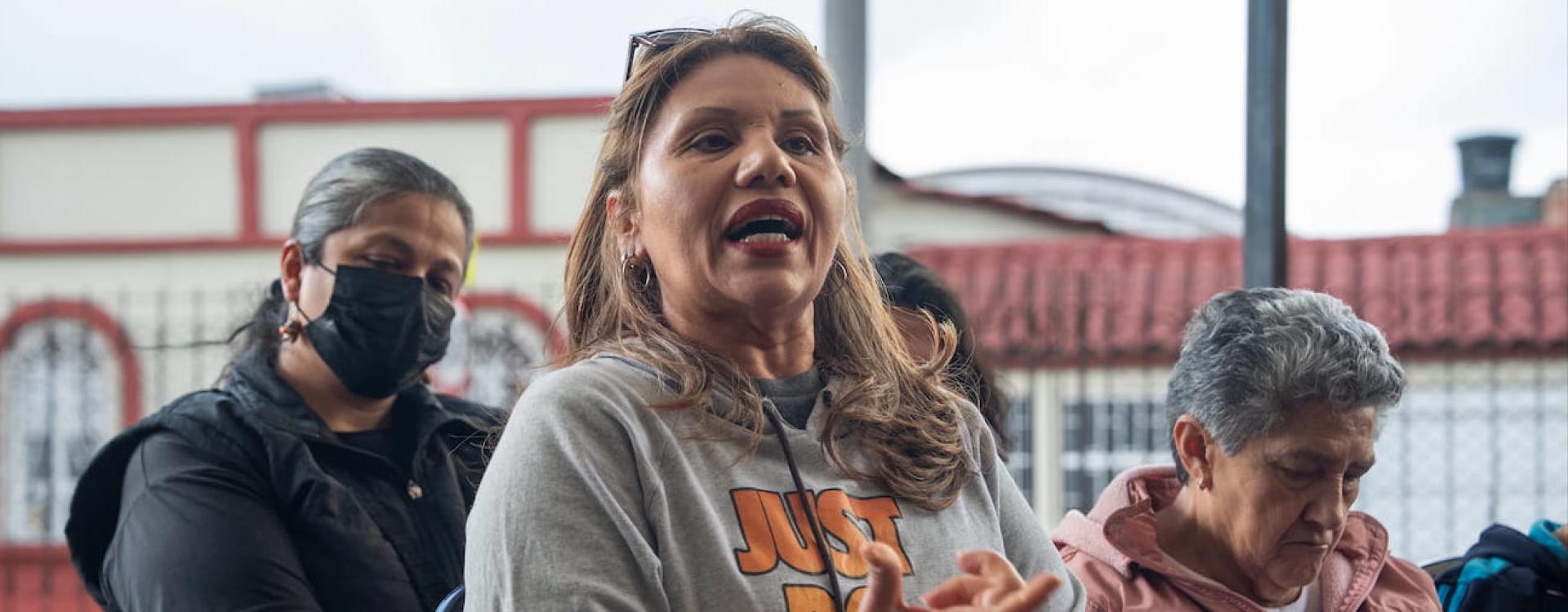 Mujer de buso gris hablando junto a otras mujeres