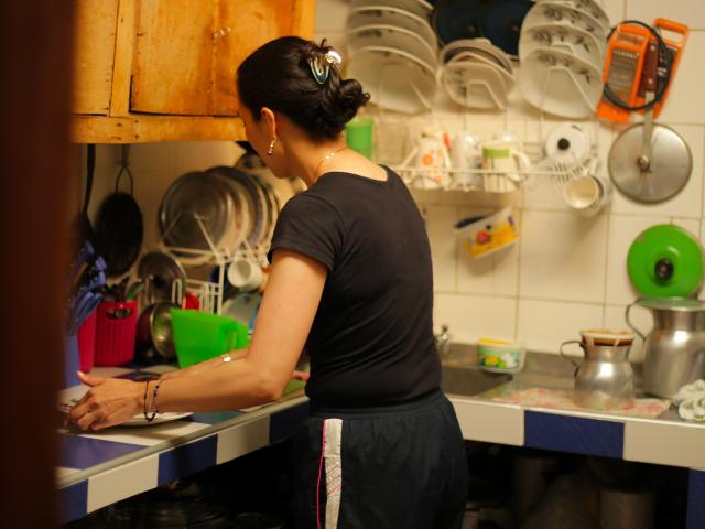 Mujer cuidadora lava platos en la cocina