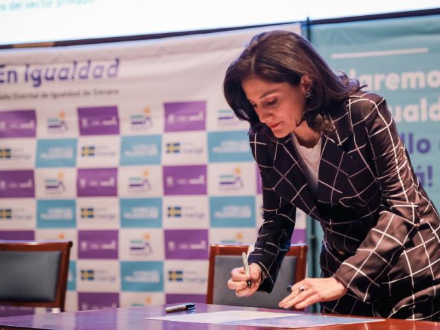 Mujer firmando pacto por la igualdad en evento