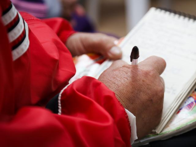 Manos de mujer mayor escribiendo en libreta