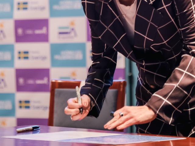 Mujer firmando pacto por la igualdad en evento