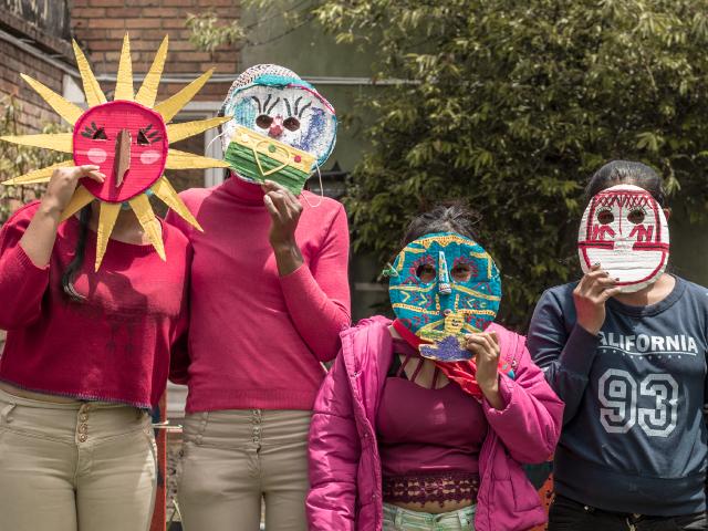 Mujeres con mascaras de cartón ocultan sus rostros